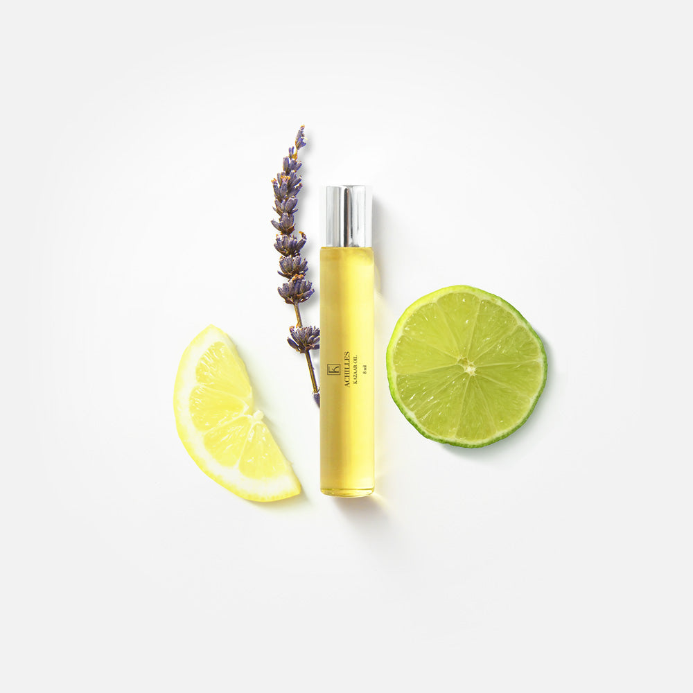 Eine gelbe Glasflasche mit silbernem Verschluss, daneben eine Lavendelblüte, eine Zitronenscheibe und eine Limettenscheibe.