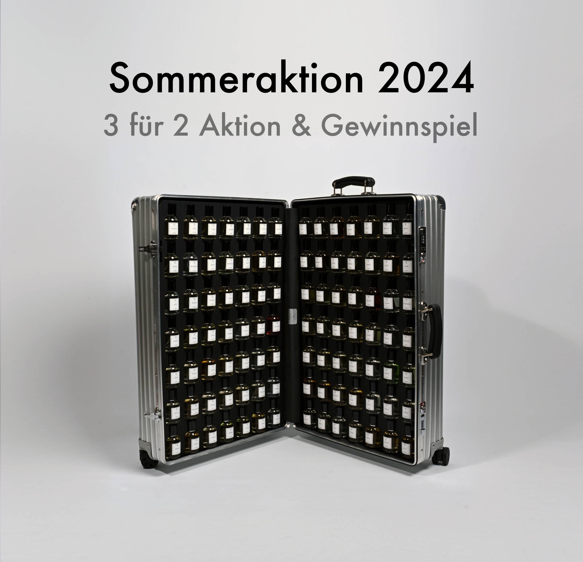 Ein silberner Koffer mit schwarzem Innenfutter steht geöffnet auf hellem Boden, darin viele kleine Fläschchen in mehreren Reihen. Darüber steht in schwarzer Schrift: „Sommeraktion 2024  3 für 2 Aktion & Gewinnspiel“. Der Koffer hat Rollen und Griff, jedes Fläschchen trägt ein weißes Etikett.